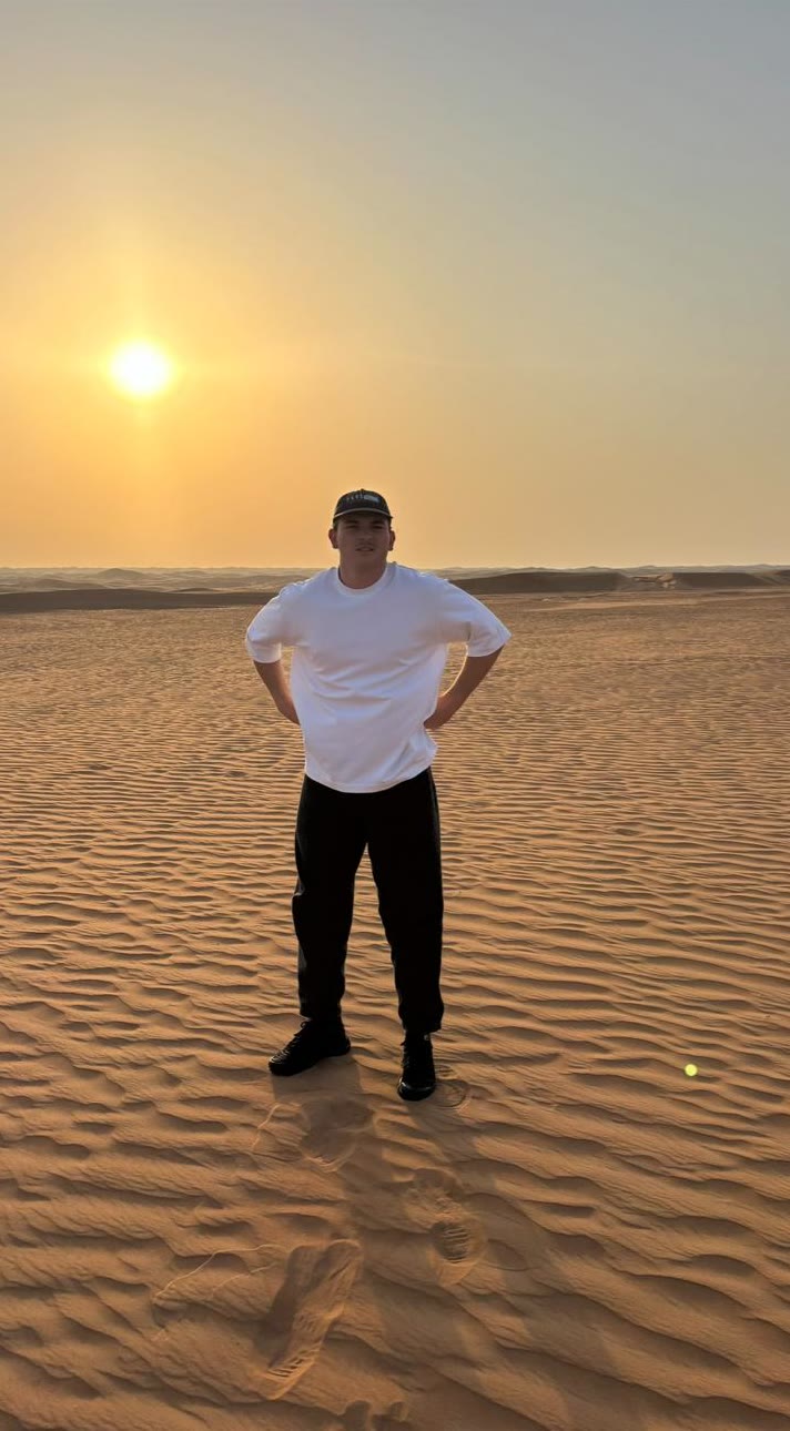 Asher standing on open dunes at sunset.